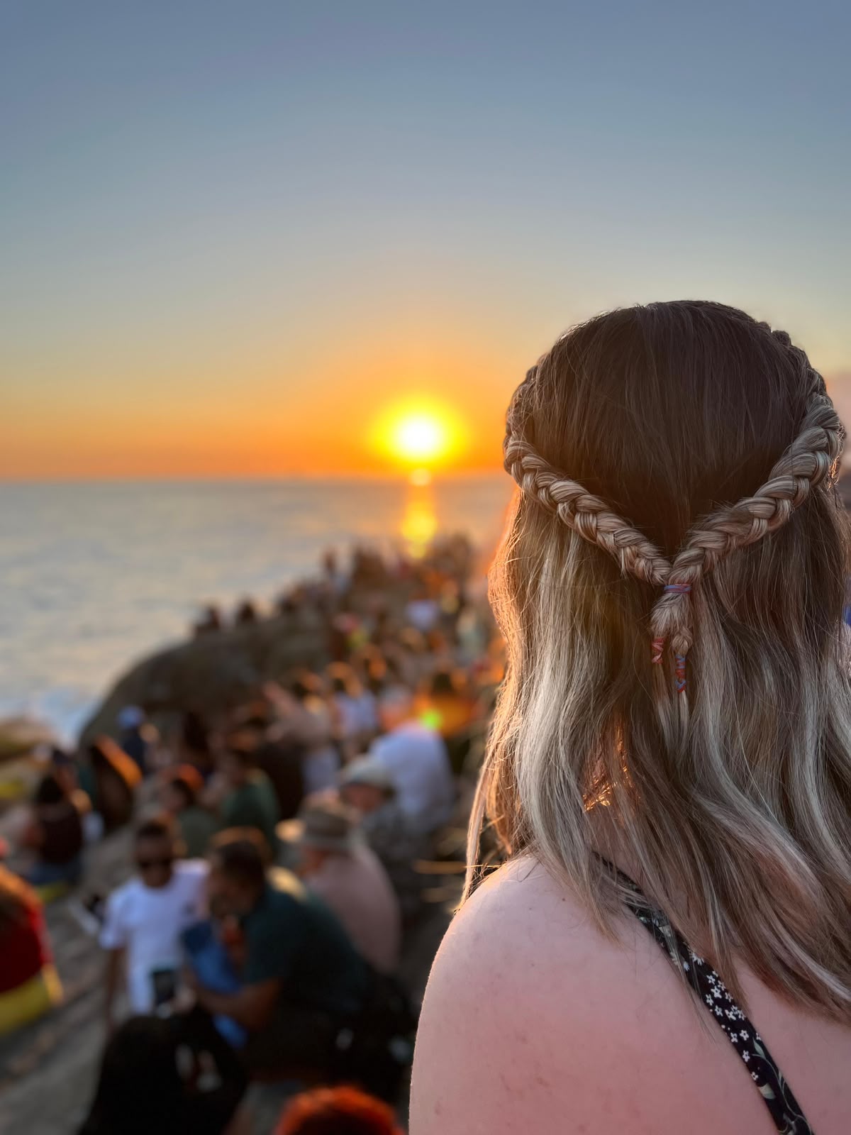 Il tramonto sull’oceano visto da uno scoglio affollato